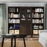 A modern dark brown wooden bookshelf filled with books, decorative items, and storage boxes.