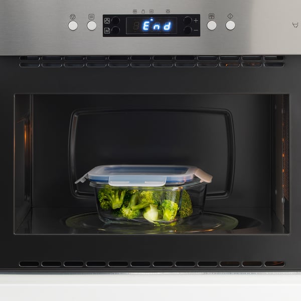 Clear glass container with lid in microwave, displaying roasted vegetables.