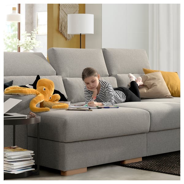 Girl drawing on ISTABY sofa with octopus toy, bright room.