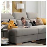 Girl drawing on ISTABY sofa with octopus toy, bright room.