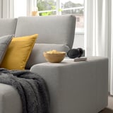 Cozy couch with adjustable headrest, yellow pillow, bowl of snacks, blanket, and headphones.