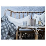 Cozy outdoor set-up: wicker furniture with blue polka dot blanket, candle, and glassware.