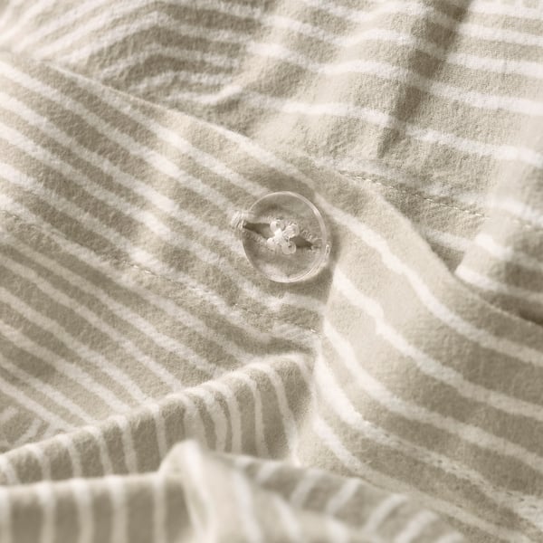 Button closure on striped duvet cover, keeping comforter secure.