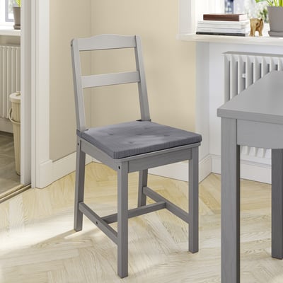 A grey JUSTINA chair with a cushioned seat. Crafted from wood and polyurethane foam, it a simple, comfortable design.