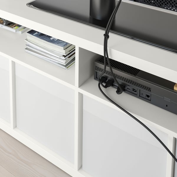 White tv bench with open back for cable management, displaying books, and electronic devices.