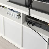 White tv bench with open back for cable management, displaying books, and electronic devices.