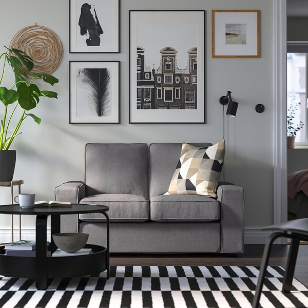 Gray KIVIK sofa, compact & cozy, low arms, patterned pillow, black/white art, checkered rug.