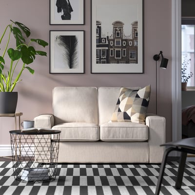 Modern living room with KIVIK sofa, pillows, rug, plant, art, and side table.