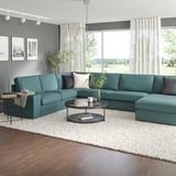 Teal l-shaped sofa in spacious living room with large windows.
