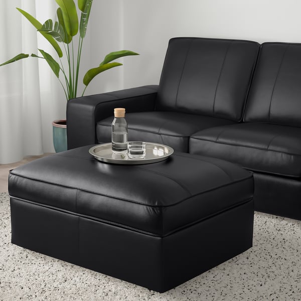 Modern living room with KIVIK sofa, footstool as table, plant.