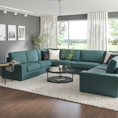 Modern living room: large teal l-shaped KIVIK sofa, dark coffee table, white rug, large window, grey walls.