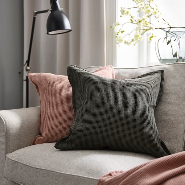 Cozy couch with gray & peach pillows, black lamp, white flowers; grey throw blanket.