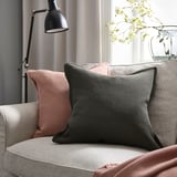 Cozy couch with gray & peach pillows, black lamp, white flowers; grey throw blanket.
