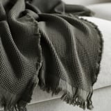 A cozy, folded black and grey striped throw blanket with fringes, showcasing its soft texture and quality craftsmanship.