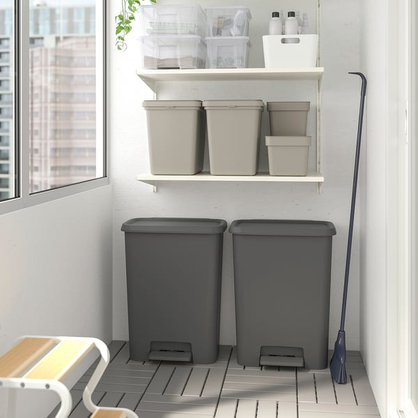 Grey plastic pedal bin with soft-close lid, large for bulky items, next to window with cleaning supplies.