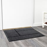 Gray door mat with black stripes on wooden floor, rubber backing for grip, suitable for high traffic areas.