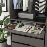 A wardrobe organizer with pull-out tray displaying accessories and clothes, ensuring easy access and visibility.