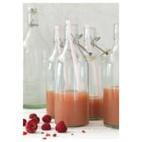 KORKEN clear glass bottles with pink strawberries, sealed with stainless steel and plastic stoppers, shown with fresh raspberries.
