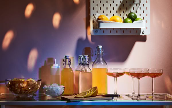 KORKEN glass jars with silicon stopper, holding drinks, ice, snacks, and lemons, placed on blue shelf under fruits basket.