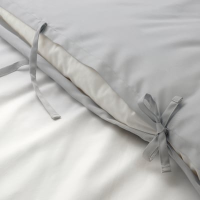 Close-up of silky grey quilt cover with decorative ribbons tied in bows, showcasing its smooth, lustrous fabric.
