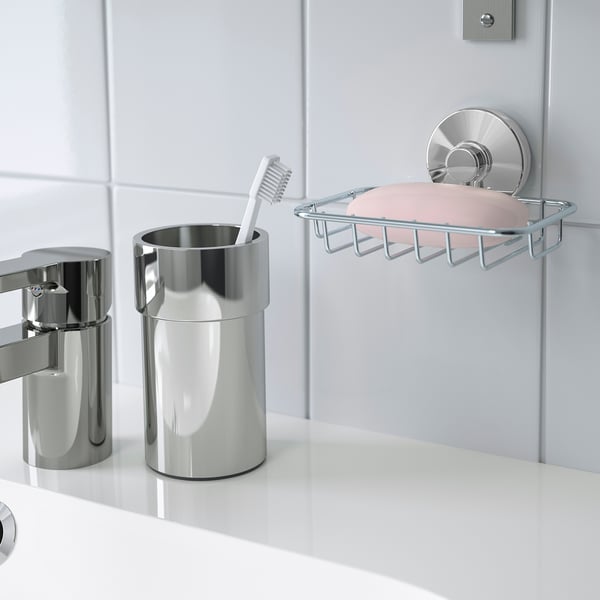 Bathroom organizer with toothbrush holder and soap dish; suction cups attach to tiles.