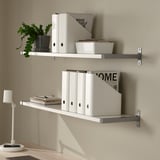 Two wall-mounted shelves holding magazine holders, books, and a plant.