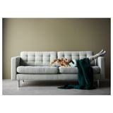 Comfy light gray sofa with one person sleeping, cozy blanket, modern minimalist design.