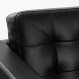 Black leather chair detail with smooth, textured surface, showing stitching and padding.