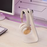 White headset stand with headphones on desk near keyboard.