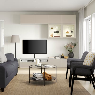 Living room with LAPPVIKEN beige cabinets, gray couch and armchair, glass coffee table, flat screen tv, and floor lamp.