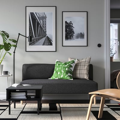 Modern living room with grey LILLEHEM sofa, green pillow, wall prints, plant, and coffee table.