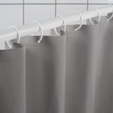 Gray shower curtain hangs from white hooks and rod, demonstrating its water-repellent and durable design.