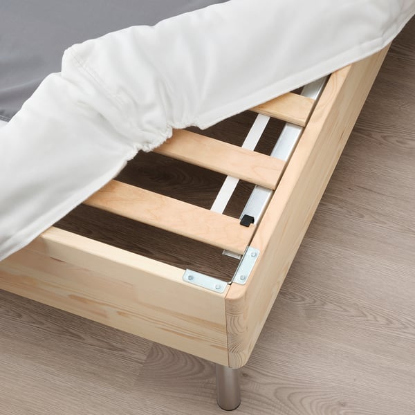 Wooden bed frame with visible slats, part of LYNGÖR base, holding white mattress and bedding.