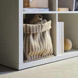 White shelf holds woven jute basket, perfect for storage.
