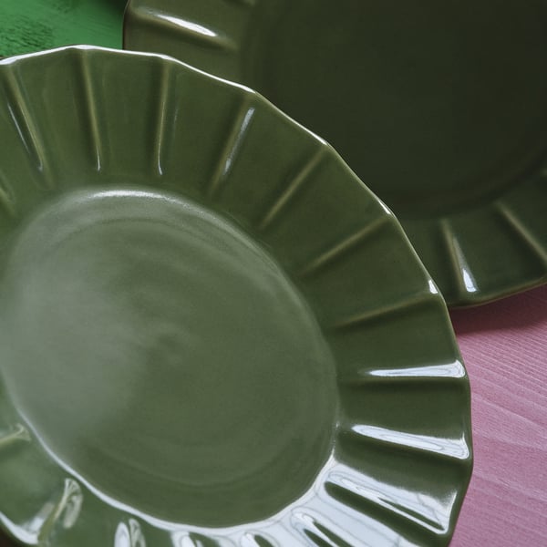 Green glazed stoneware plate with raised, intricate edge pattern. Smooth, polished surface; elegant, durable design.