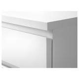 Modern white dresser with clean lines and drawers, one slightly open.