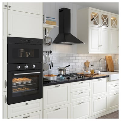 Modern kitchen with double oven, sleek black stove, white cabinets, wooden utensils, and hanging cookware.