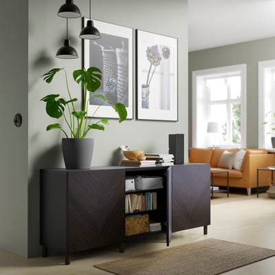 Modern living room with dark wood cabinet, plant, books, speaker, and orange sofas.