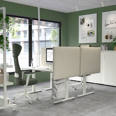 Modern office with MITTZON beige acoustic screens, grey fabric, dividers on desks, green walls, big window, plants, and contemporary decor.