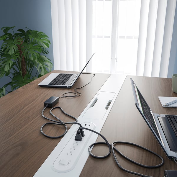 A modern conference table with built-in power outlets and cable management, accommodating laptops and promoting an organized workspace.