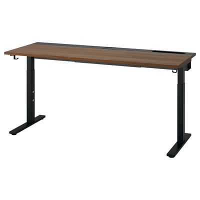 The MITTZON desk a rectangular wooden top with a brown finish and black metal legs, designed for height adjustment and cable management.