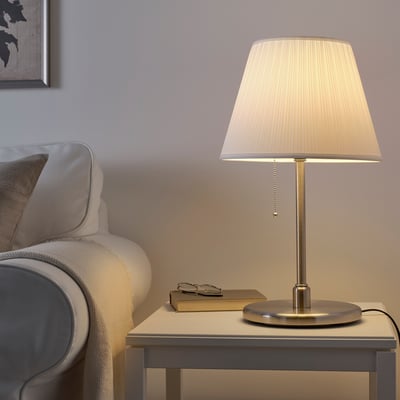 MYRHULT lamp with cream shade beside gray chair.