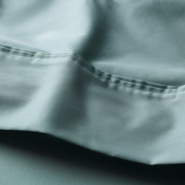 Smooth, silky sheet in blue-green with lustrous sheen, pleated edge, woven from lyocell and cotton for comfort.