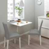 Small kitchen nook with white foldable table and gray chairs; minimalist design.