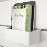 A tablet and book titled red dog sit upright on a shelf from a wall-mounted storage unit.