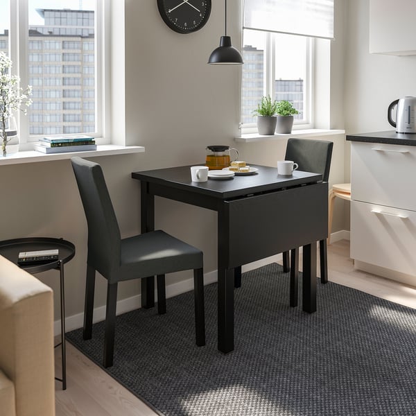 Small modern black NORDVIKEN drop-leaf table and chairs by window, perfect for compact spaces.