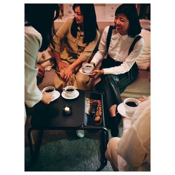 Three women enjoying tea on striped sofa with OLSERÖD table.