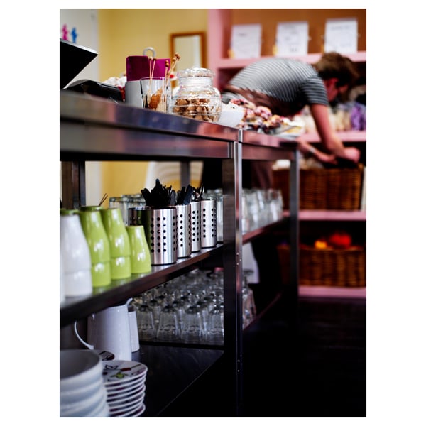 Shelves with stacked cups, cutlery, and jars in a kitchen setting.