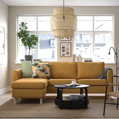Mustard-yellow sectional sofa by window, coffee table, pendant light, and plant.