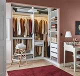 Modern, organized closet with hangers, shelves, and storage boxes. White interior, wooden floor, and red rug. Efficient space usage.